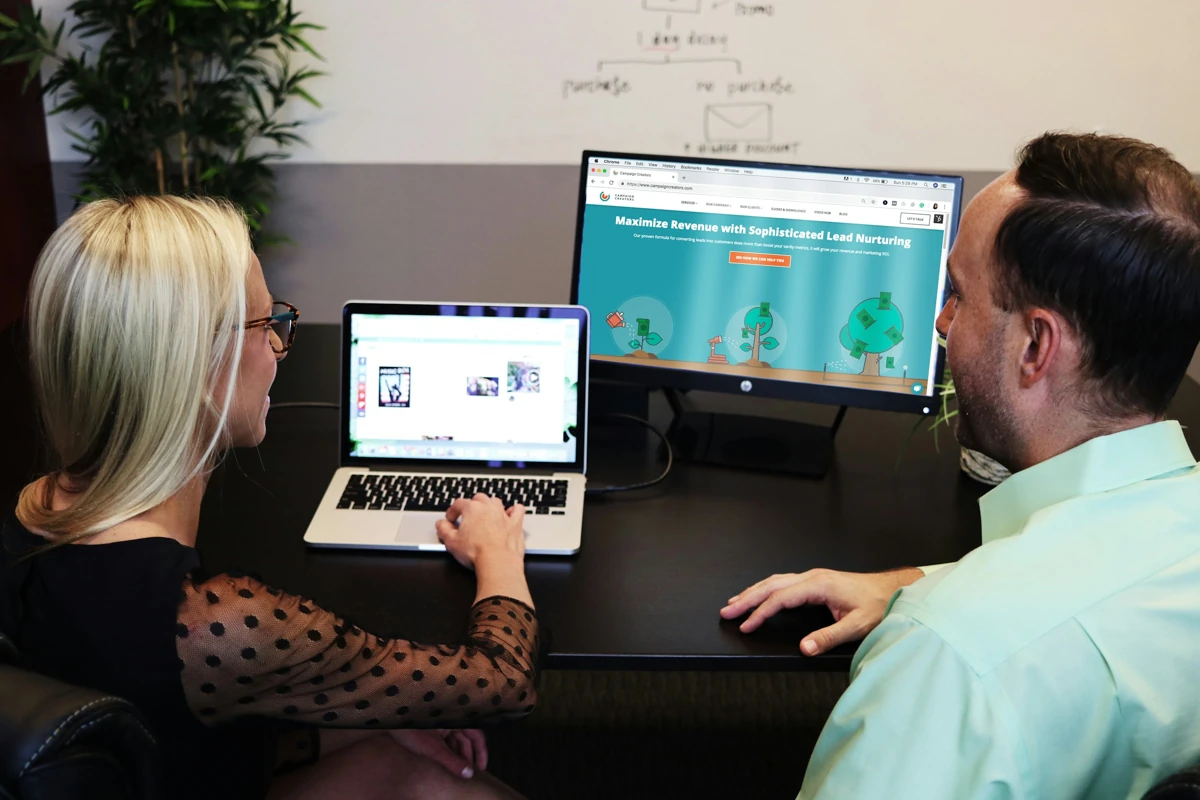 Two colleagues discussing work at a table with laptops