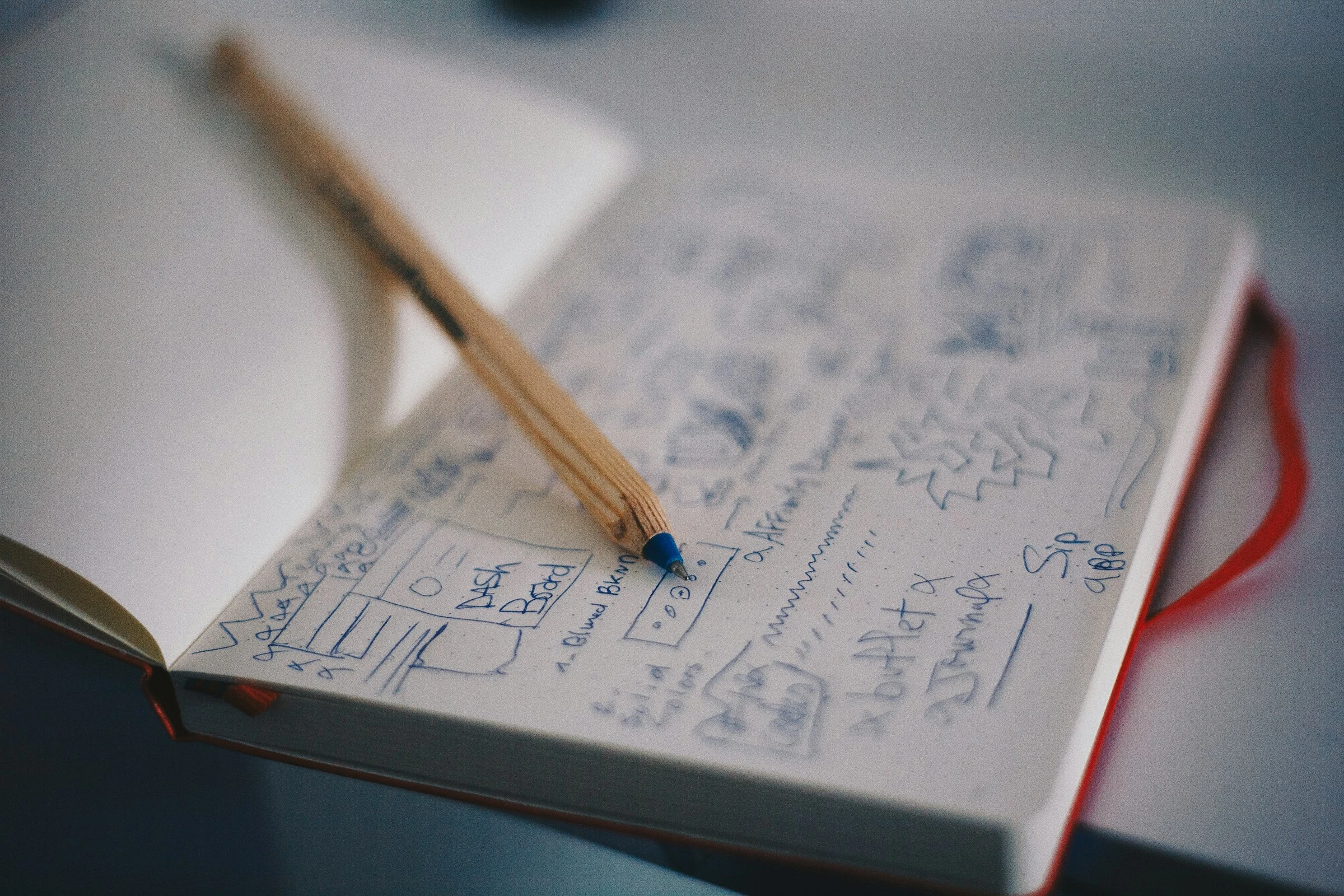 Pencil resting on hand-drawn interface wireframes